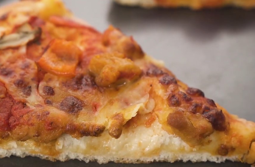 A close-up of a pizza slice, showcasing the melted cheese and various toppings
