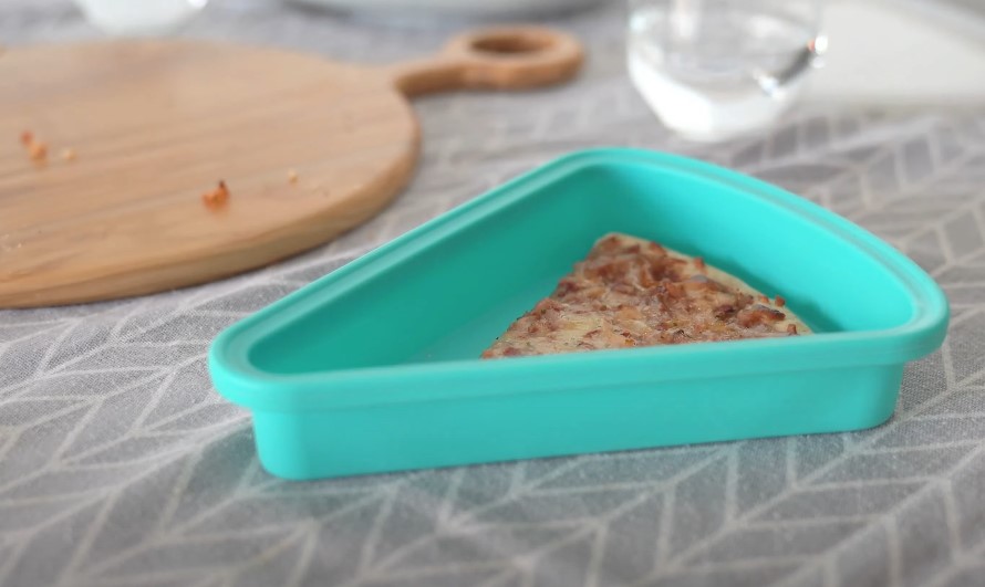 A single slice of pizza rests in a teal silicone mold