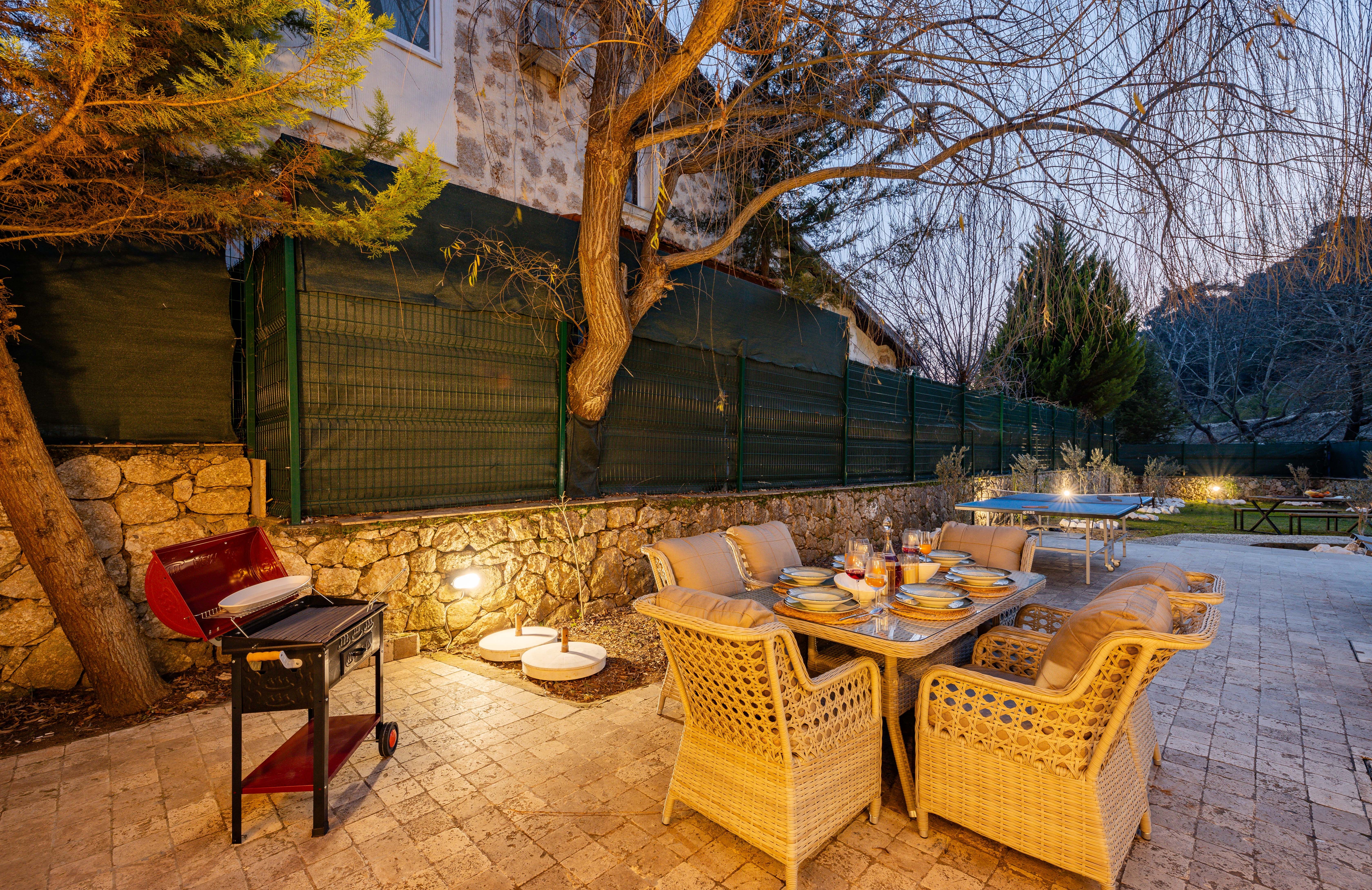 Backyard patio with dining table and barbecue grill at dusk