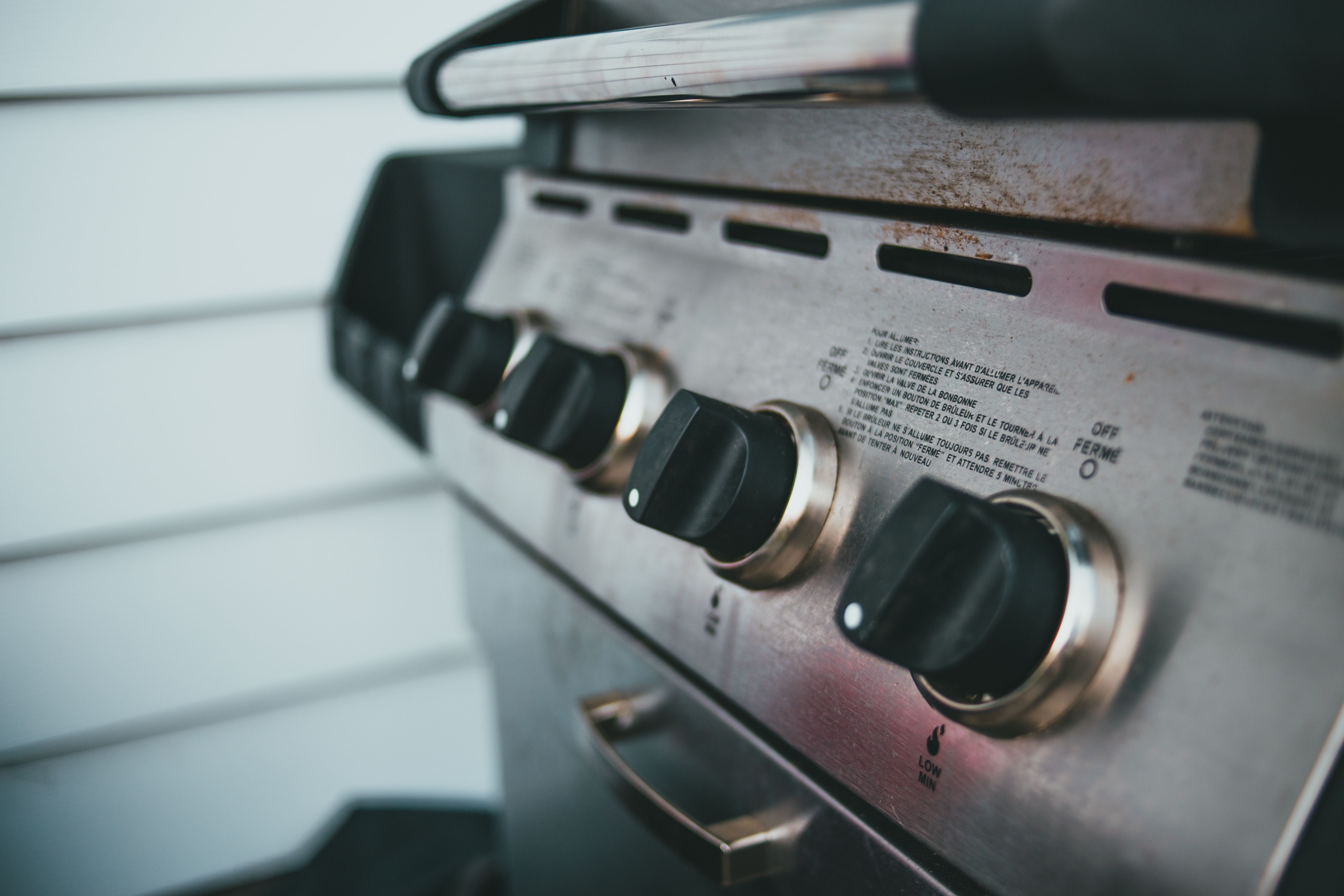 Close-up of barbecue grill controls with knobs and stainless steel surface